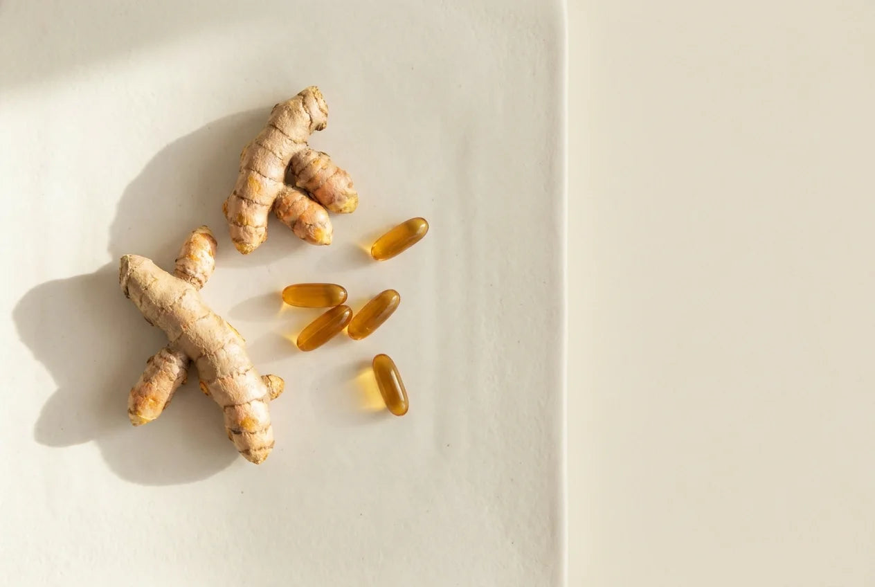 Turmeric root and omega softgels on a porcelain surface